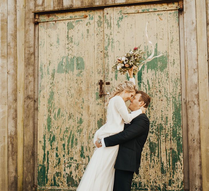 Groom picks up new wife wearing bridal jumper