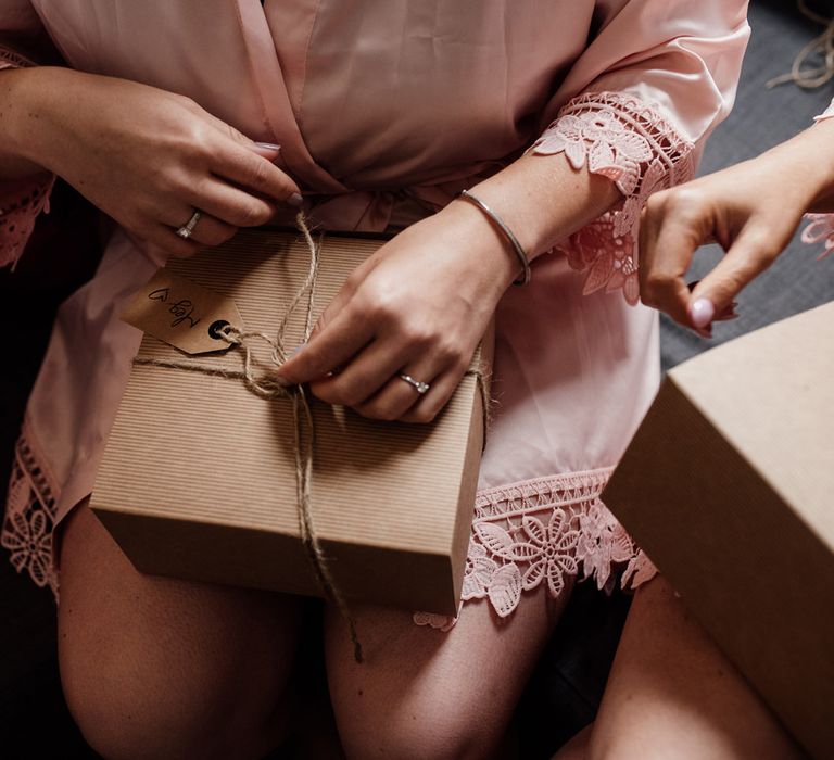 Bridesmaid in pink getting ready robe opening a parcel by Aberdeen wedding photographer