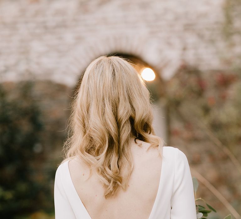 Bride in Long Sleeved Andrea Hawkes Dress with Bateau Neck and Low V-Back with Buttons | Bridal Bouquet with Eucalyptus, White Roses, White and Blue Thistles and Ferns | Emerald Green Bridesmaid Dress for a Winter Wedding at Middleton Lodge | Georgina Harrison Photography