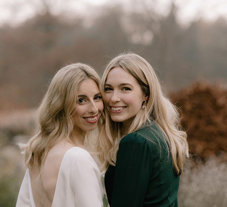 Bride in Long Sleeved Andrea Hawkes Dress with Bateau Neck and Low V-Back with Buttons | Bridesmaid in Forest Green Reformation Dress with Long Sleeves | Emerald Green Bridesmaid Dress for a Winter Wedding at Middleton Lodge | Georgina Harrison Photography