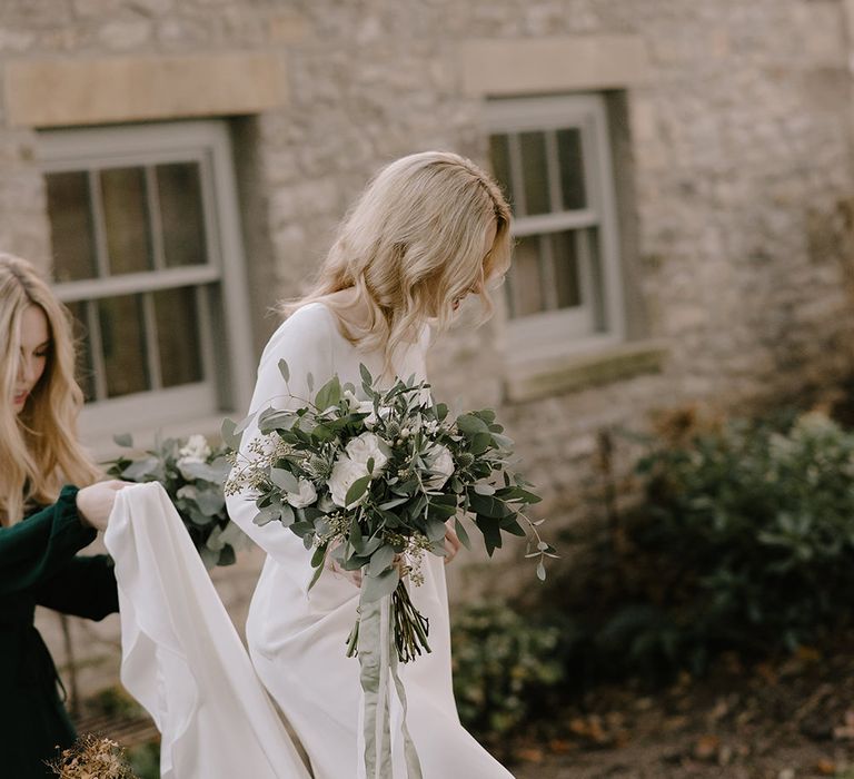 Bride in Long Sleeved Andrea Hawkes Dress with Bateau Neck and Low V-Back with Buttons | Bridesmaid in Forest Green Reformation Dress with Long Sleeves | Wedding Bouquets with Eucalyptus, White Roses, White and Blue Thistles and Ferns | Emerald Green Bridesmaid Dress for a Winter Wedding at Middleton Lodge | Georgina Harrison Photography