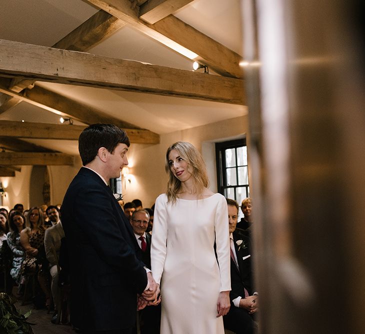 Bride in Long Sleeved Andrea Hawkes Dress with Bateau Neck and Low V-Back with Buttons | Groom in Navy Three-Piece Suit from Suit Supply with Green Tie | Emerald Green Bridesmaid Dress for a Winter Wedding at Middleton Lodge | Georgina Harrison Photography