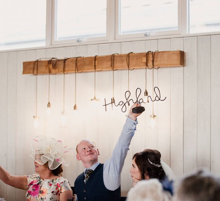 Groom holding up a wire table name sign