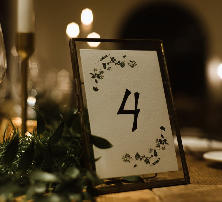 Table Number in Gold Frame | White Tapered Candle | Gold Candlestick | Emerald Green Bridesmaid Dress for a Winter Wedding at Middleton Lodge | Georgina Harrison Photography