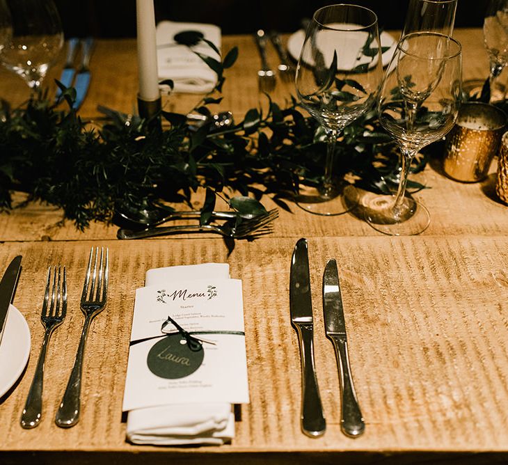 Wedding Breakfast Menu Tied with Ribbon | Foliage Table Runners | White Tapered Candles | Gold Candlesticks | Gold Tea Light Holders | Emerald Green Bridesmaid Dress for a Winter Wedding at Middleton Lodge | Georgina Harrison Photography