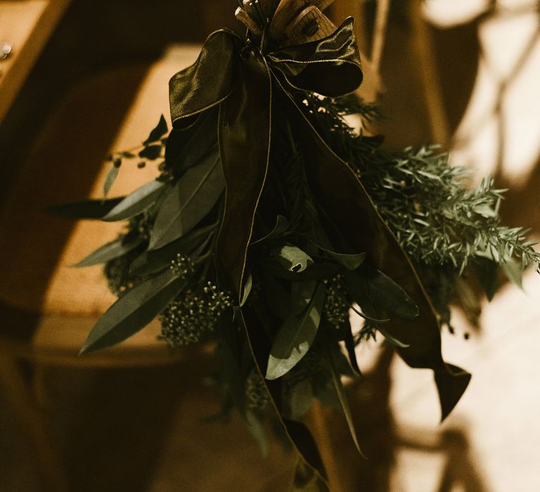 Foliage Chair Accessory Tied with Green Ribbon | Emerald Green Bridesmaid Dress for a Winter Wedding at Middleton Lodge | Georgina Harrison Photography