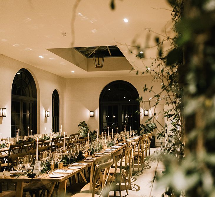 Wooden Banquet Tables | Foliage Table Runners | White Tapered Candles | Gold Candlesticks | Gold Tea Light Holders | Gold Framed Table Numbers | Wedding Reception at The Fig House at Middleton Lodge | Emerald Green Bridesmaid Dress for a Winter Wedding at Middleton Lodge | Georgina Harrison Photography