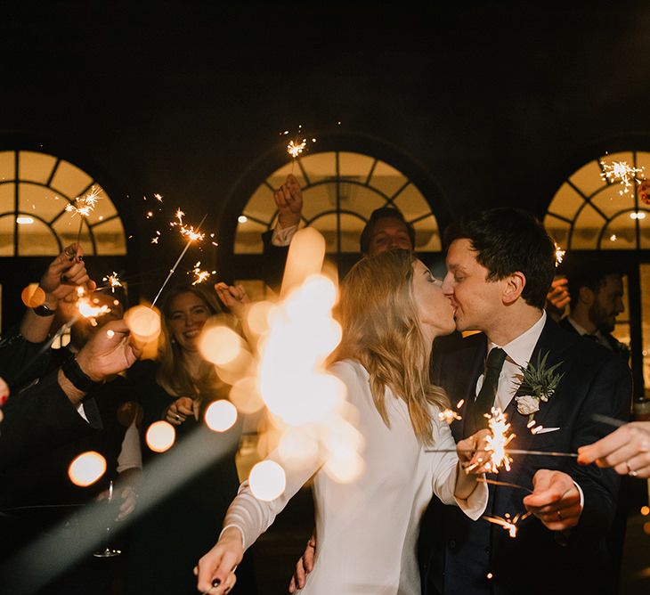 Bride in Long Sleeved Andrea Hawkes Dress with Bateau Neck and Low V-Back with Buttons | Groom in Navy Three-Piece Suit from Suit Supply with Green Tie | Sparkler Send Off | Emerald Green Bridesmaid Dress for a Winter Wedding at Middleton Lodge | Georgina Harrison Photography