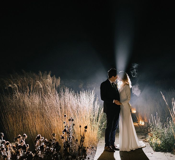 Bride in Long Sleeved Andrea Hawkes Dress with Bateau Neck and Low V-Back with Buttons | Groom in Navy Three-Piece Suit from Suit Supply with Green Tie | Emerald Green Bridesmaid Dress for a Winter Wedding at Middleton Lodge | Georgina Harrison Photography