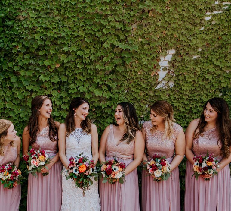 Bride in Sleeveless High-Neck Stella York Gown with Lace Overlay and Gold Underskirt | Bridesmaids in Pink Dresses with Lace Bodice | Colourful Bouquets of Pink, Orange and White Flowers with Ferns, Eucalyptus and Greenery | Rifle Paper Co. Trainers for Informal Wedding in Fort Worth, Texas | Paul &amp; Nanda Photography