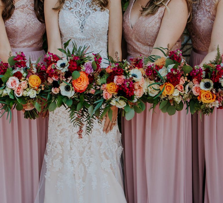 Colourful Bouquets of Pink, Orange and White Flowers with Ferns, Eucalyptus and Greenery | Bride in Sleeveless High-Neck Stella York Gown with Lace Overlay and Gold Underskirt | Bridesmaids in Pink Dresses with Lace Bodice | Rifle Paper Co. Trainers for Informal Wedding in Fort Worth, Texas | Paul &amp; Nanda Photography