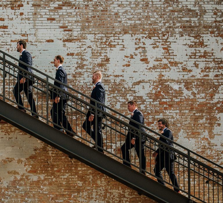 Groom's Party on Staircase at BRIK | Groom in Navy Suit and Floral Tie | Groomsmen in Navy Suits and Silk Blush Ties | Rifle Paper Co. Trainers for Informal Wedding in Fort Worth, Texas | Paul &amp; Nanda Photography