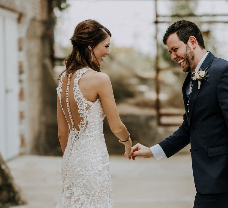 First Look Photo | Bride in Sleeveless High-Neck Stella York Gown with Lace Overlay and Gold Underskirt | Half Up Half Down Wedding Hair | Groom in Navy Suit and Floral Tie | Rifle Paper Co. Trainers for Informal Wedding in Fort Worth, Texas | Paul &amp; Nanda Photography