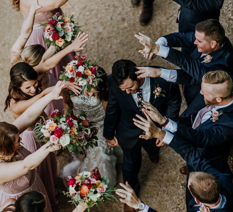 Bride in Sleeveless High-Neck Stella York Gown with Lace Overlay and Gold Underskirt | Groom in Navy Suit and Floral Tie | Bridesmaids in Pink Dresses with Lace Bodice | Colourful Bouquets of Pink, Orange and White Flowers with Ferns, Eucalyptus and Greenery | Groomsmen in Navy Suits and Silk Blush Ties | Pink Buttonholes | Rifle Paper Co. Trainers for Informal Wedding in Fort Worth, Texas | Paul &amp; Nanda PhotographyRifle Paper Co. Trainers for Informal Wedding in Fort Worth, Texas | Paul &amp; Nanda Photography