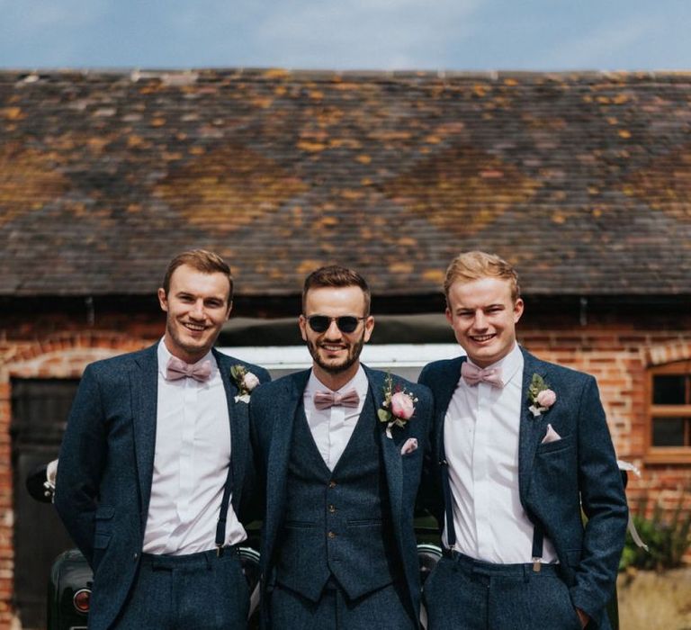 Groom and groomsmen in navy suits with pink buttonholes