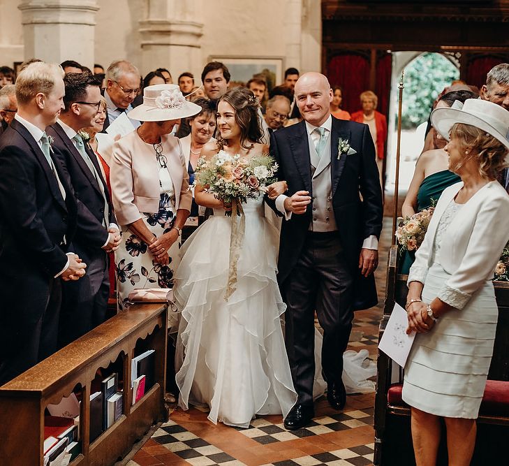 Bride inlayered wedding dress walks down the church aisle