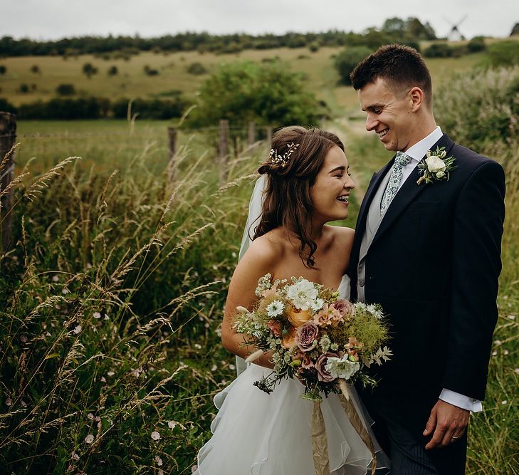 Bride in layered wedding dress with groom in morning suit