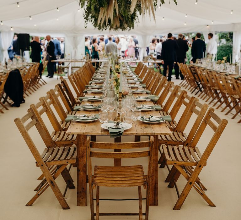 Long wooden banquet tables with foliage hanging installation