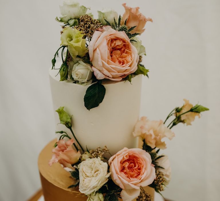 White and gold wedding cake with flower decor