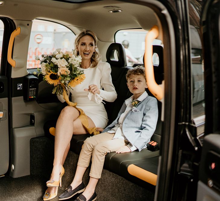 Stylish bride in short wedding dress and son in a taxi cab