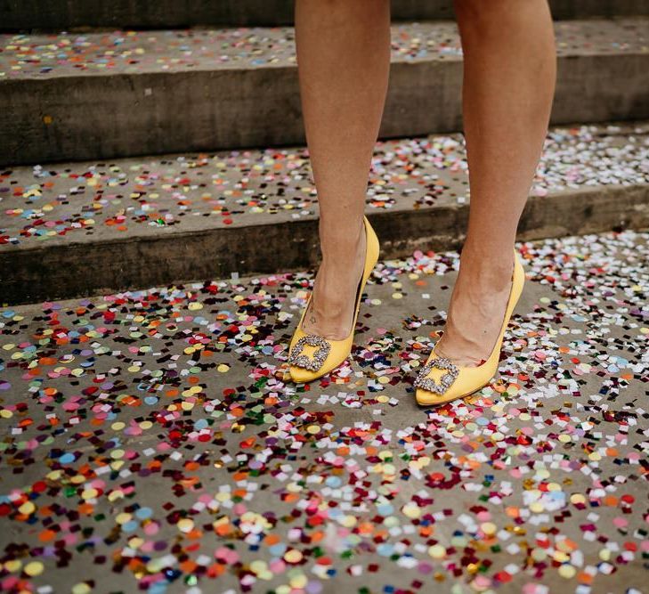 Bride in Yellow Manolo Blahnik shoes standing on colourful confetti