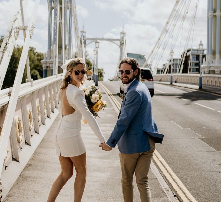 Stylish bride and groom walking across at bride in London