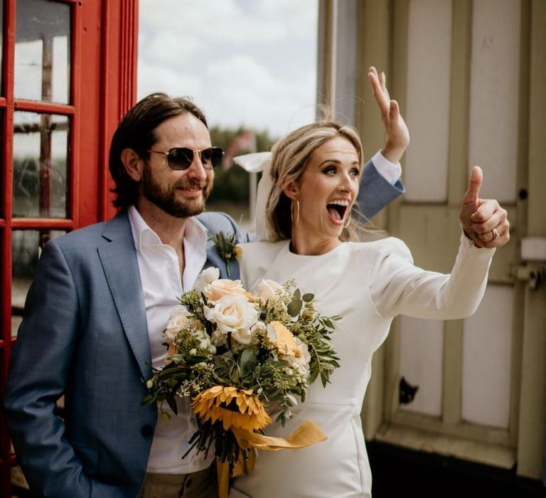 Bride in short wedding dress putting her thumbs up to on lookers