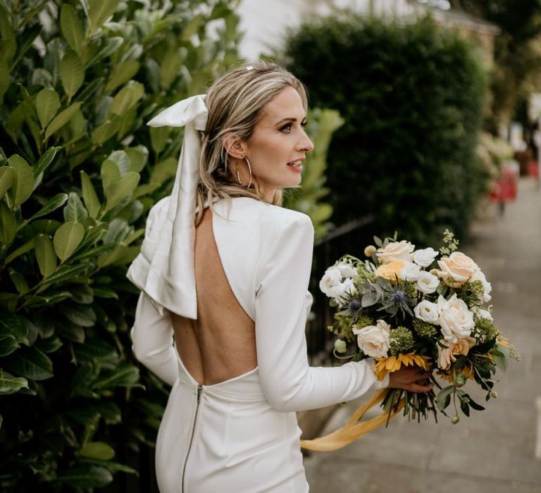 Stylish bride in Alex Perry wedding dress with low back and bow hair accessory