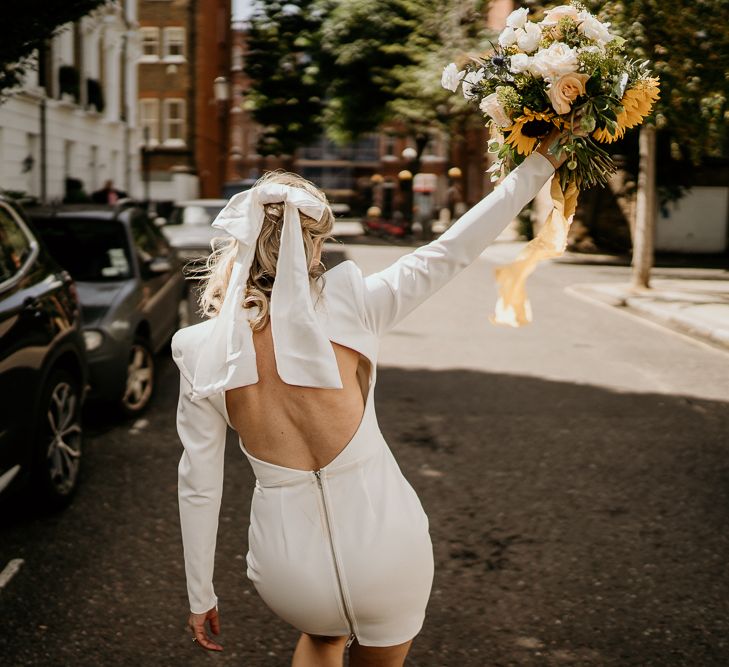 Bride in backless short wedding dress with bow hair accessory