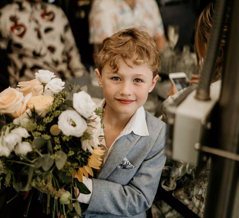 Little groomsman holding the yellow flower wedding bouquet