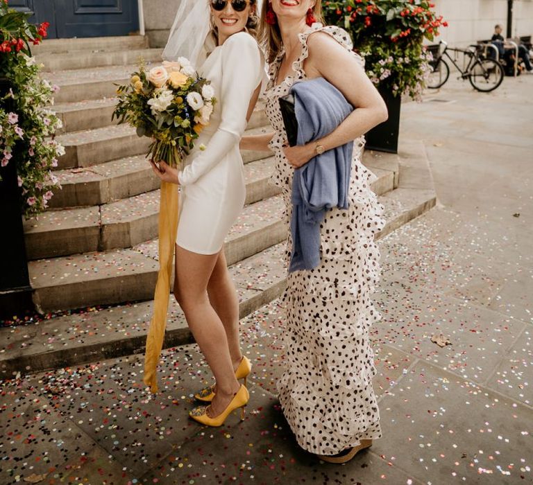 Stylish bride in short wedding dress with friend in polka dot dress