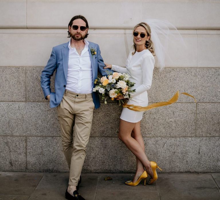 Stylish bride in short wedding dress and groom in blue blazer and chino at London wedding