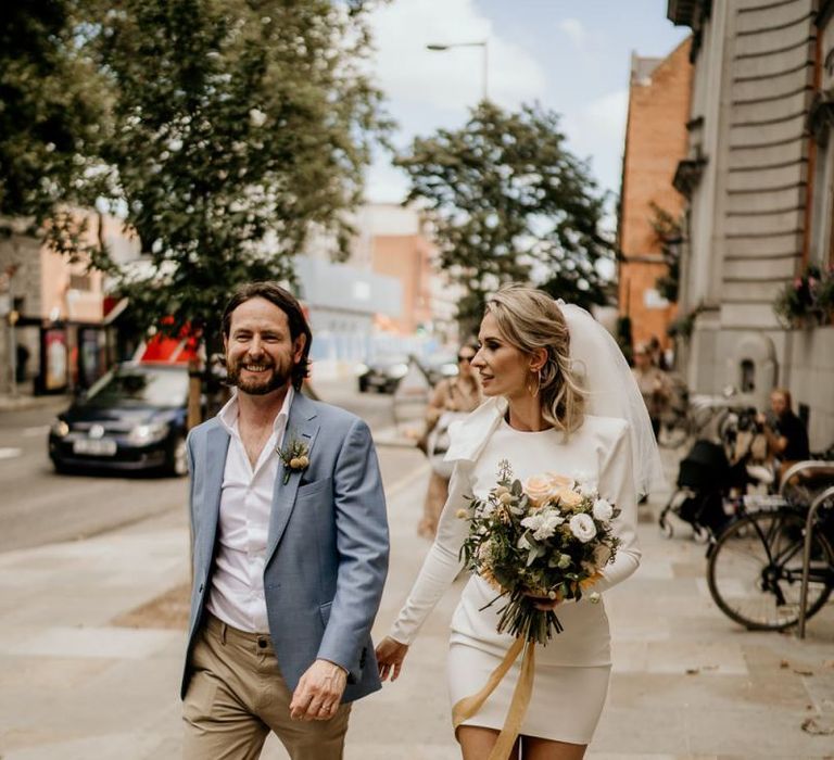 Stylish bride and groom walking through London