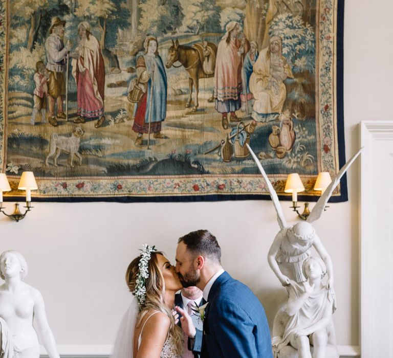 Wedding Ceremony at Elmore Court with Bride in Mikaella Wedding Dress and Groom in Bespoke Navy Check Suit Kissing at the Altar