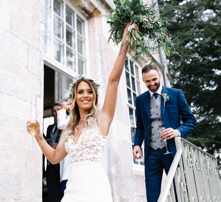 Bride in Fitted Mikaella Wedding Dress with Lace Bodice and Groom in Bespoke Navy Check Suit Exiting the Wedding Ceremony