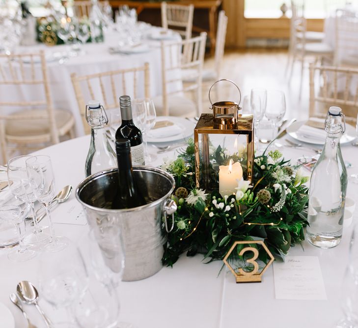 Table Centrepiece Lantern Surrounded by White and Green Wedding Flowers