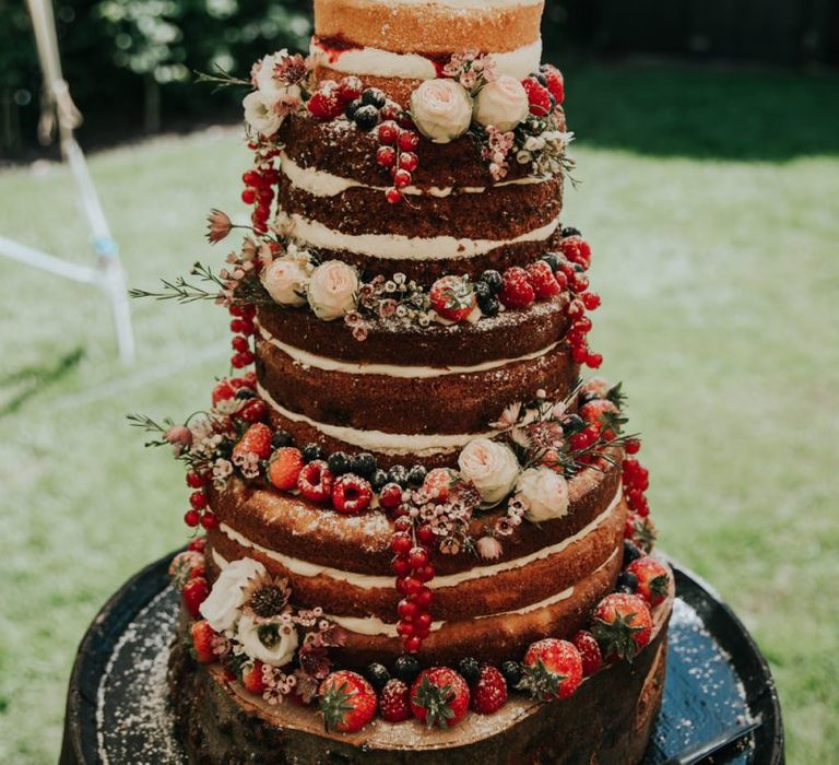 Naked wedding cake with berries and cake topper