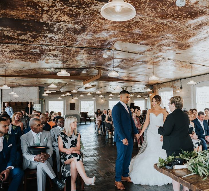 Wedding Ceremony | Bride in Fishtail Allure Bridal Gown | Groom in Navy Ted Baker Suit | Pink Roll Top Booze Bath and Copper &amp; Perspex Wedding Decor at Industrial Venue The West Mill | Rosie Kelly Photography