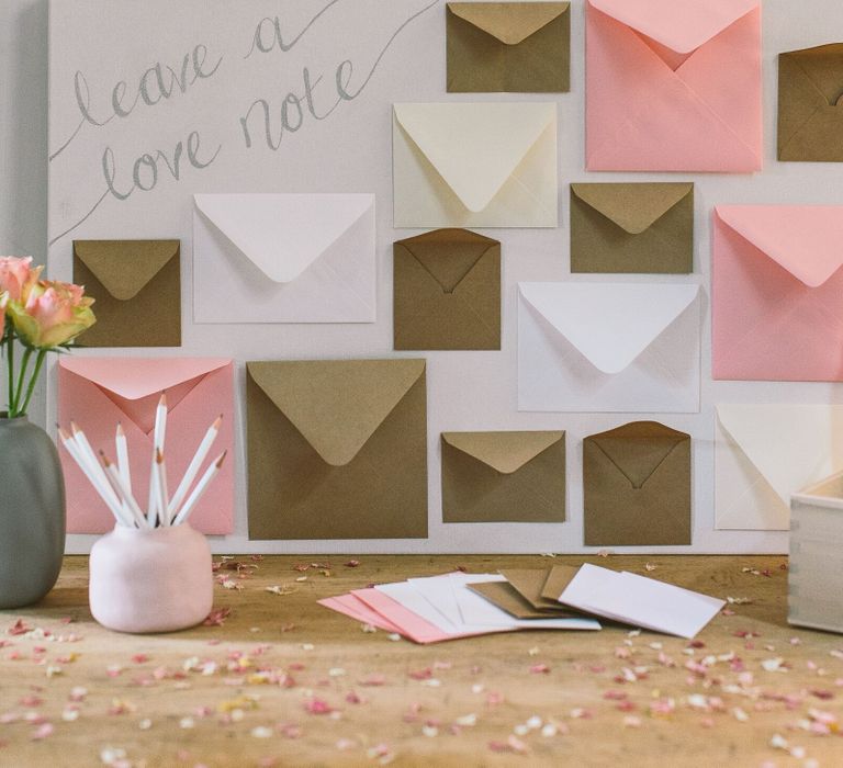 Wedding card table with pencils, flowers, a box for guests to leave their wedding cards in, and envelopes to post notes to the bride and groom into