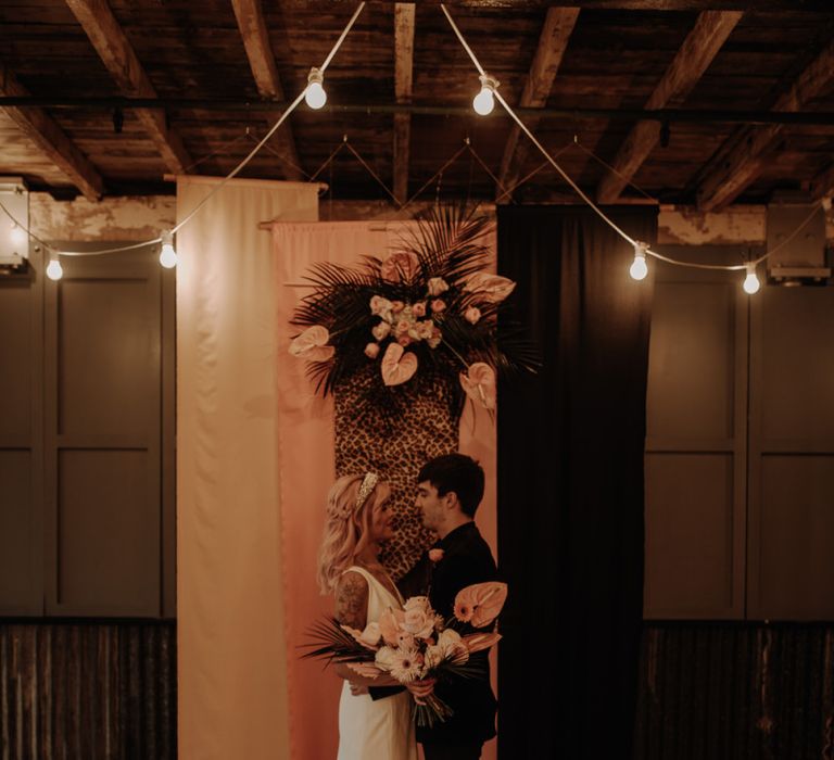 Bride and groom standing in front of fabric backdrop