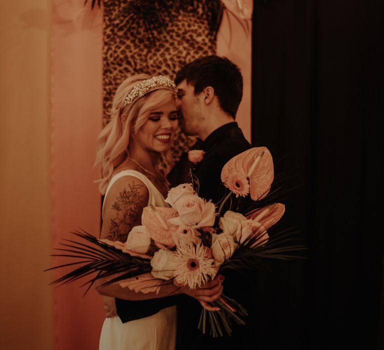 Bride holding a blush tropical bouquet with anthuriums, roses and gerberas