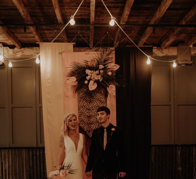 Stylish bride and groom standing in from tof blush and leopard print drapes