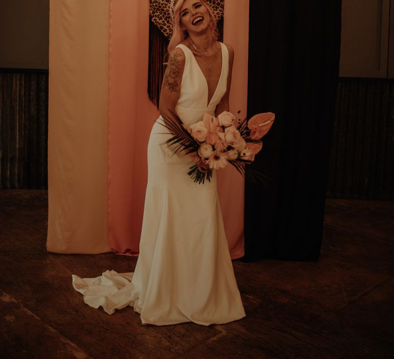 Stylish bride in minimalist wedding dress holding a tropical bouquet