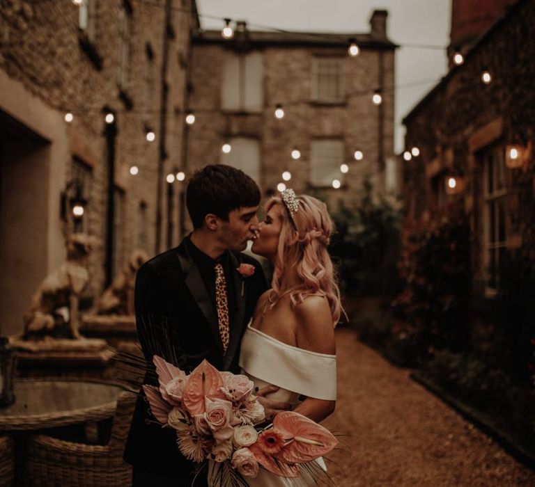 Stylish bride in off the shoulder dress under festoon lights