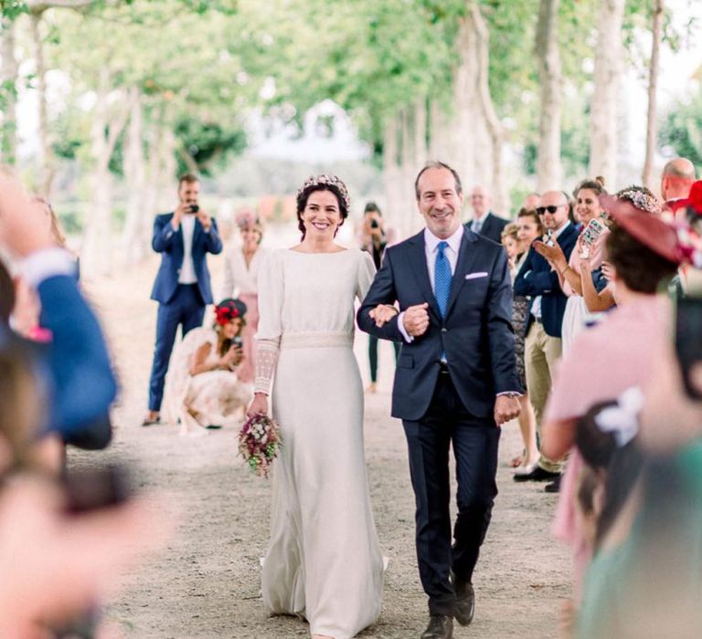 Wedding ceremony bridal entrance with bride walking down the aisle in Victoria Imaz dress