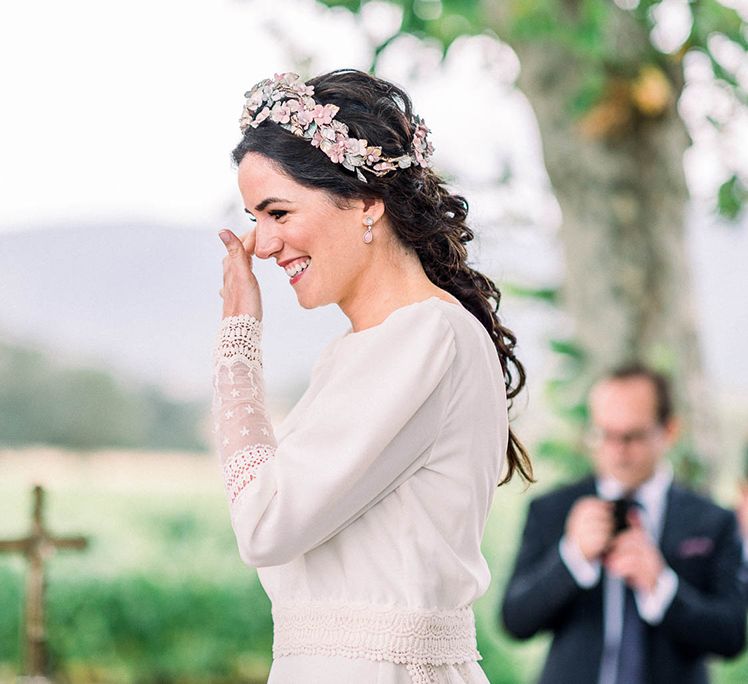 Emotional bride wiping away tears at the wedding ceremony in a pink flower headdress