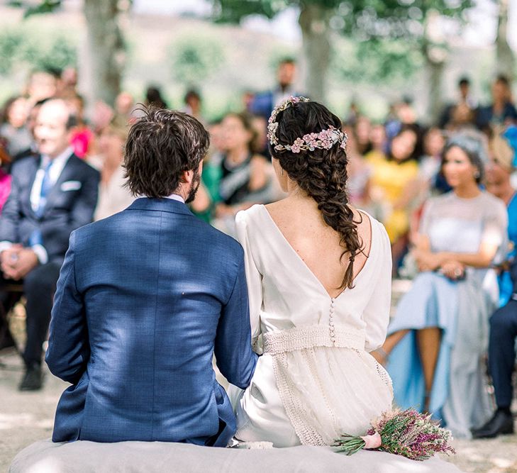 Bride in low V back wedding dress with  fishtail braid,  flower headdress and astilbe wedding bouquet