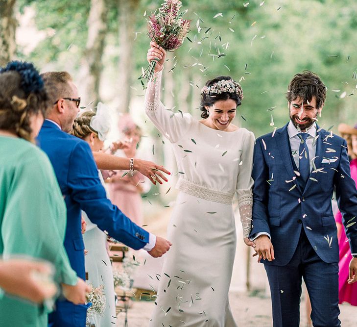 Olive leaf confetti exit with bride holding her astilbe wedding bouquet in the air