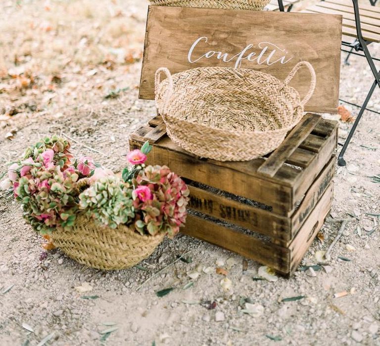 Rustic wedding decor with wooden sign, crates and wicker baskets filled with flowers