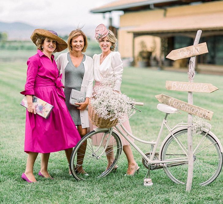 Wedding guests posing by a vintage bicycle filled with gypsophila